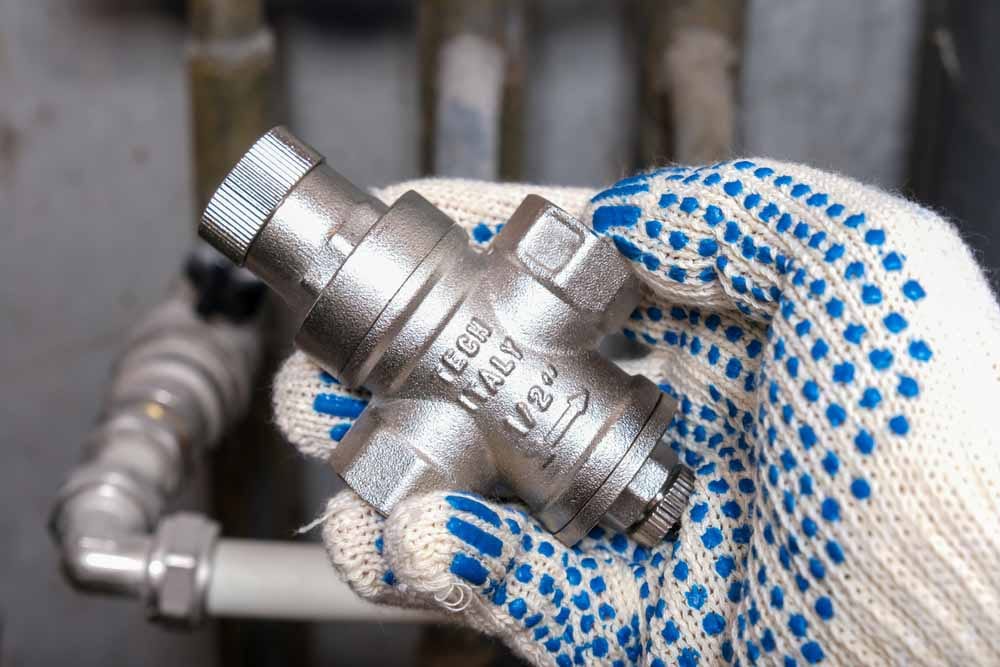 Gloved hand holding a pressure-reducing valve
