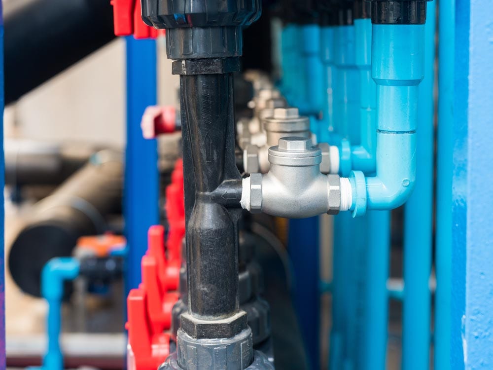 Row of check valves on blue and black plastic water pipes
