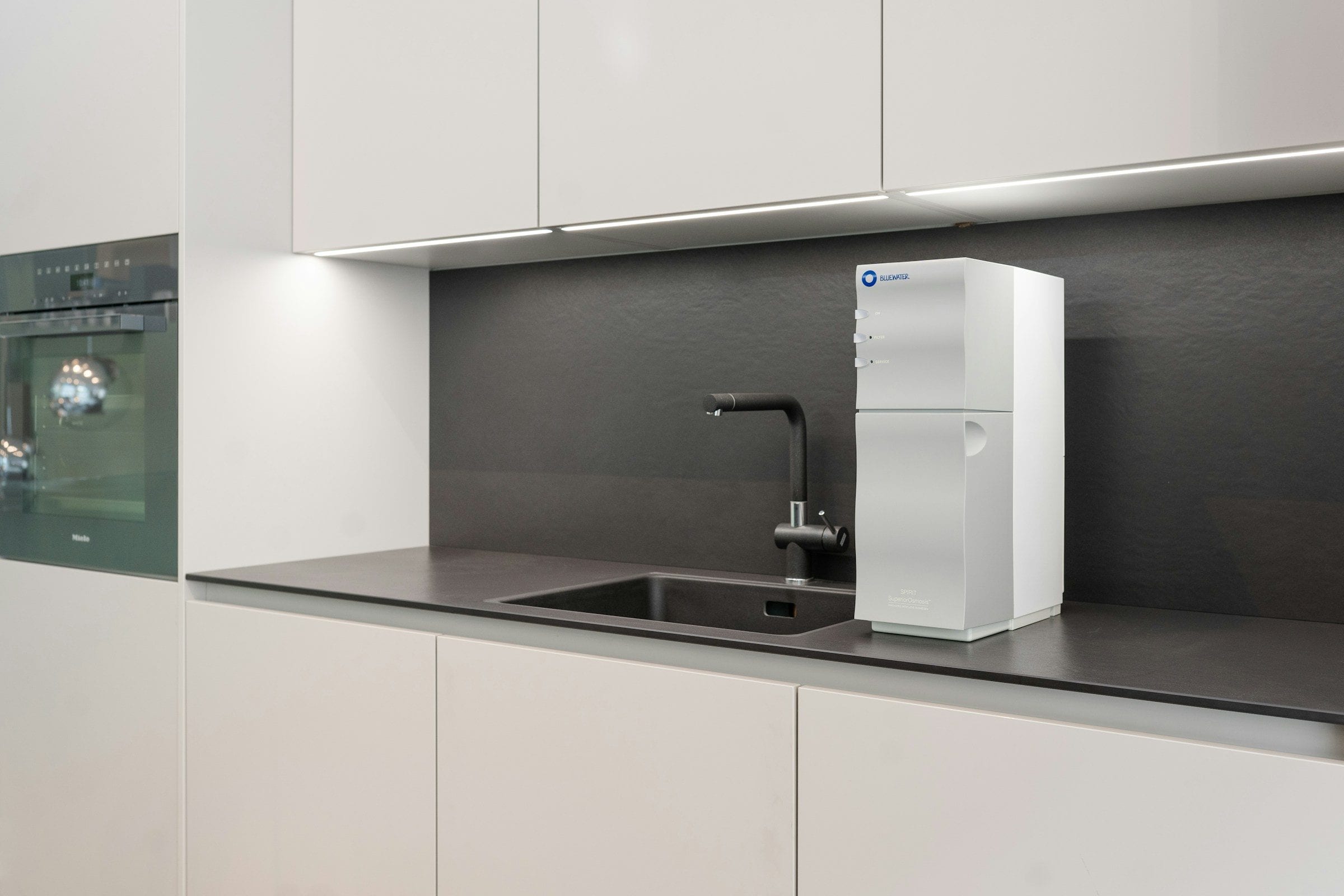 A modern kitchen with a countertop water purifier beside the sink
