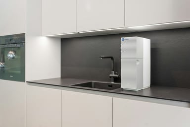 A modern kitchen with a countertop water purifier beside the sink