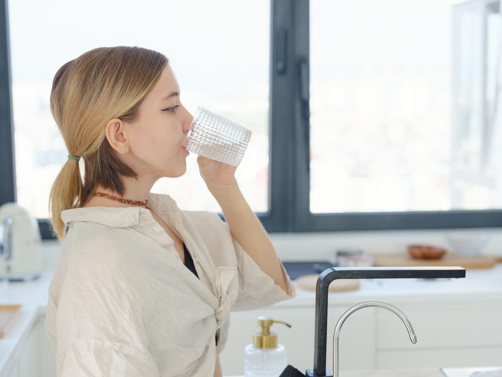 person drinking water from the tap